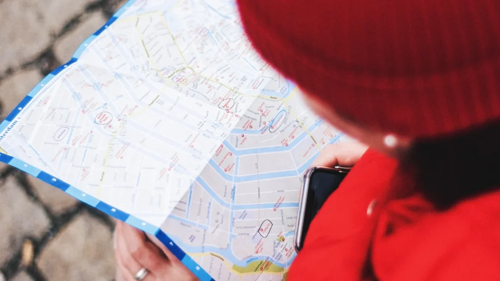 Personne consultant un plan de ville et son smartphone pour trouver un commerce proche