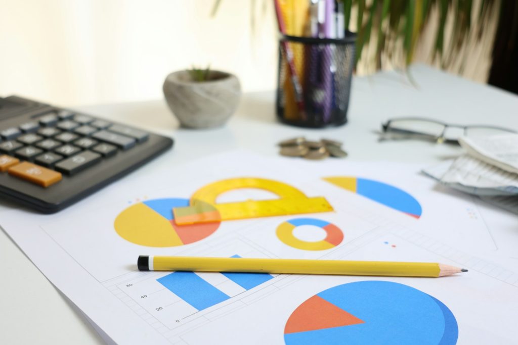 Calculatrice, graphiques et crayon sur un bureau pour calculer le coût du portage salarial